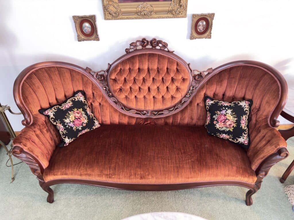 Antique rose velvet sofa with an ornate carved wooden frame at an Estate Greats sale