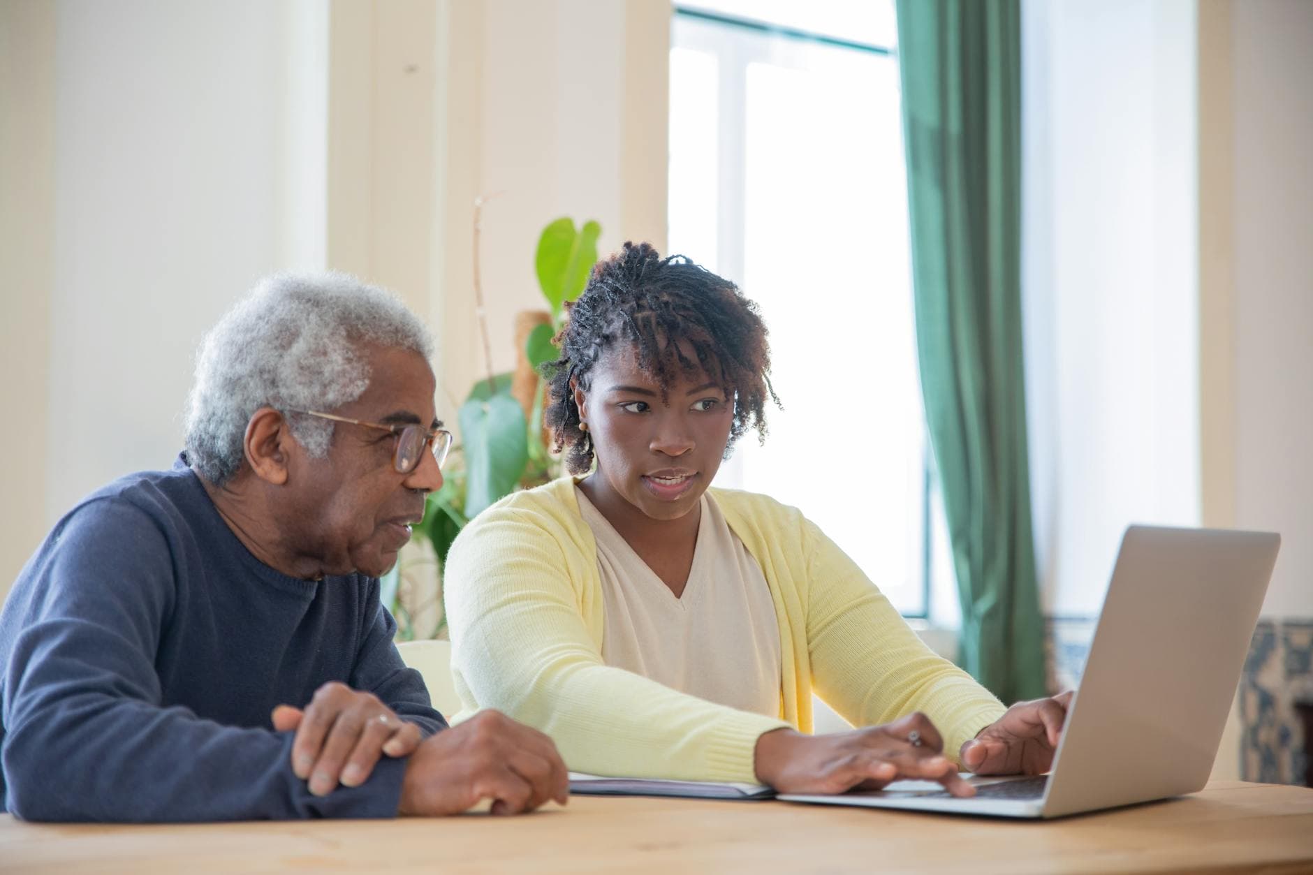 An older man and a younger woman reviewing something together on a laptop at home