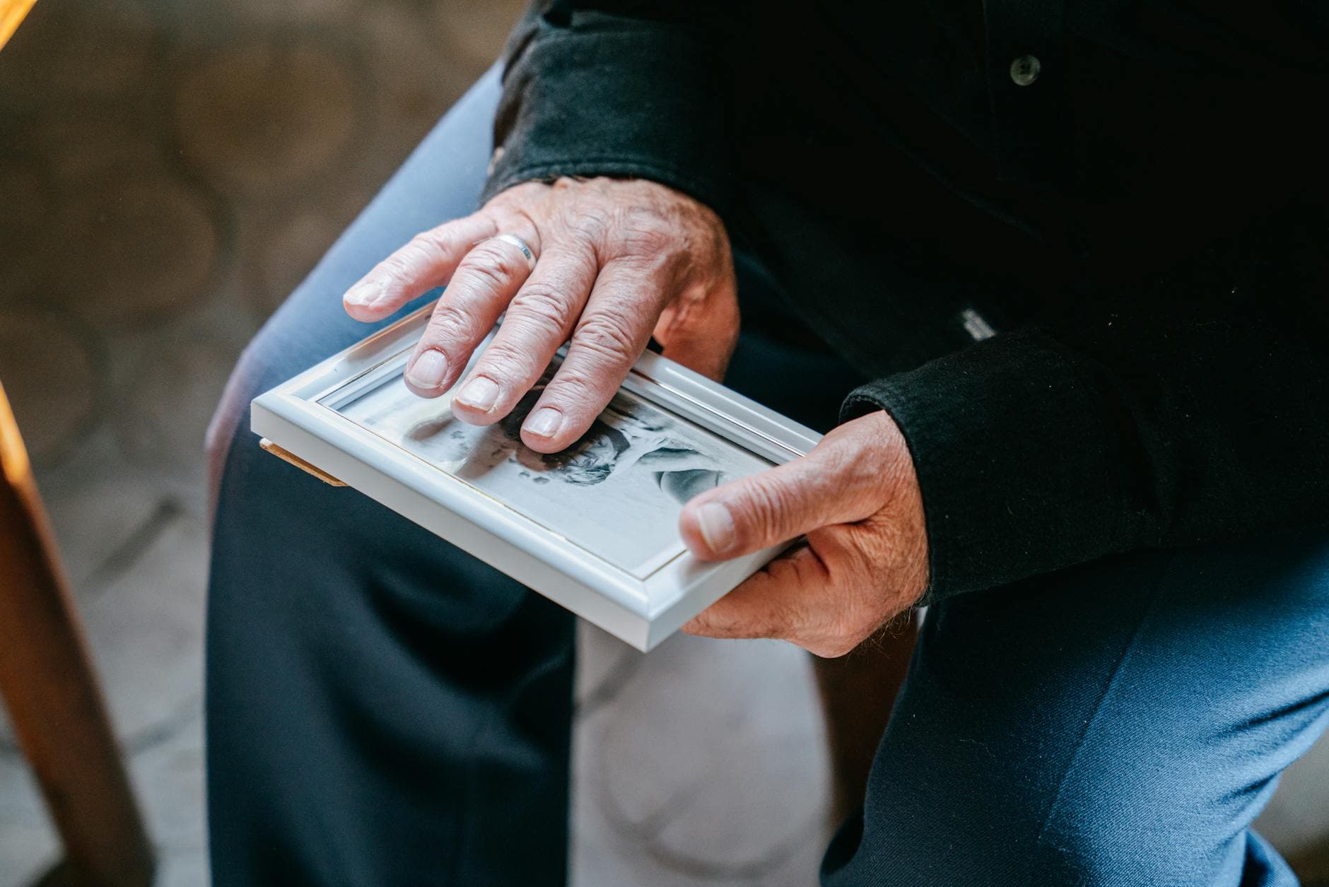 An older person holding a small framed photograph in both hands