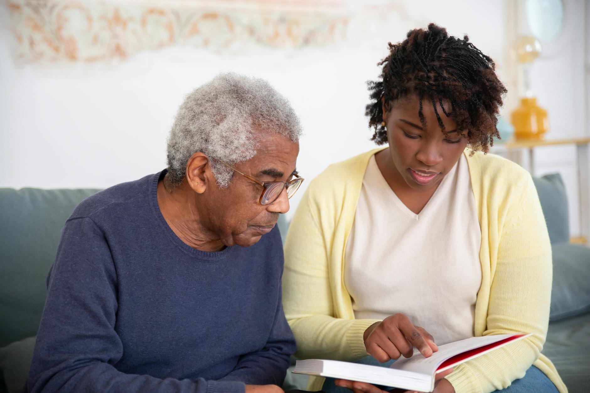 a woman in yellow cardigan talking to the man while reading a book